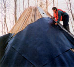 Ashirah lays mats of recycled rubber to waterproof the structure. The orange vest makes her more visible to passing hunters.